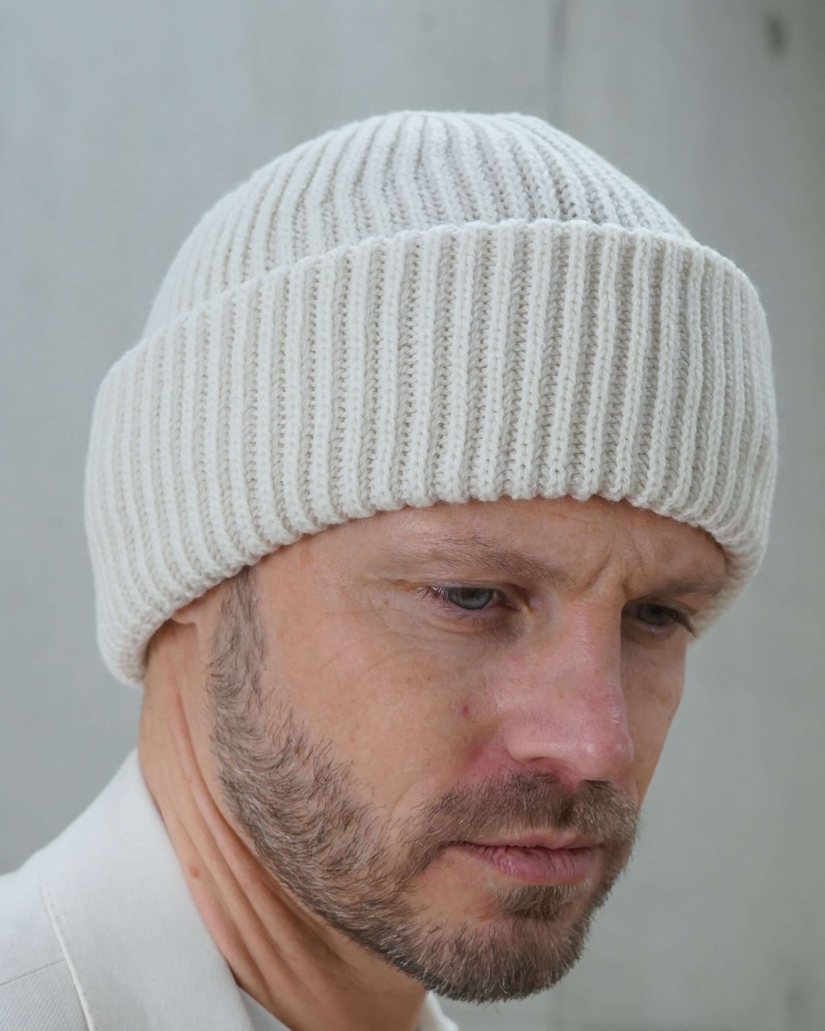 Kopfansicht eines Mannes mit Beanie-Wollmütze schneeweiss seitwärts