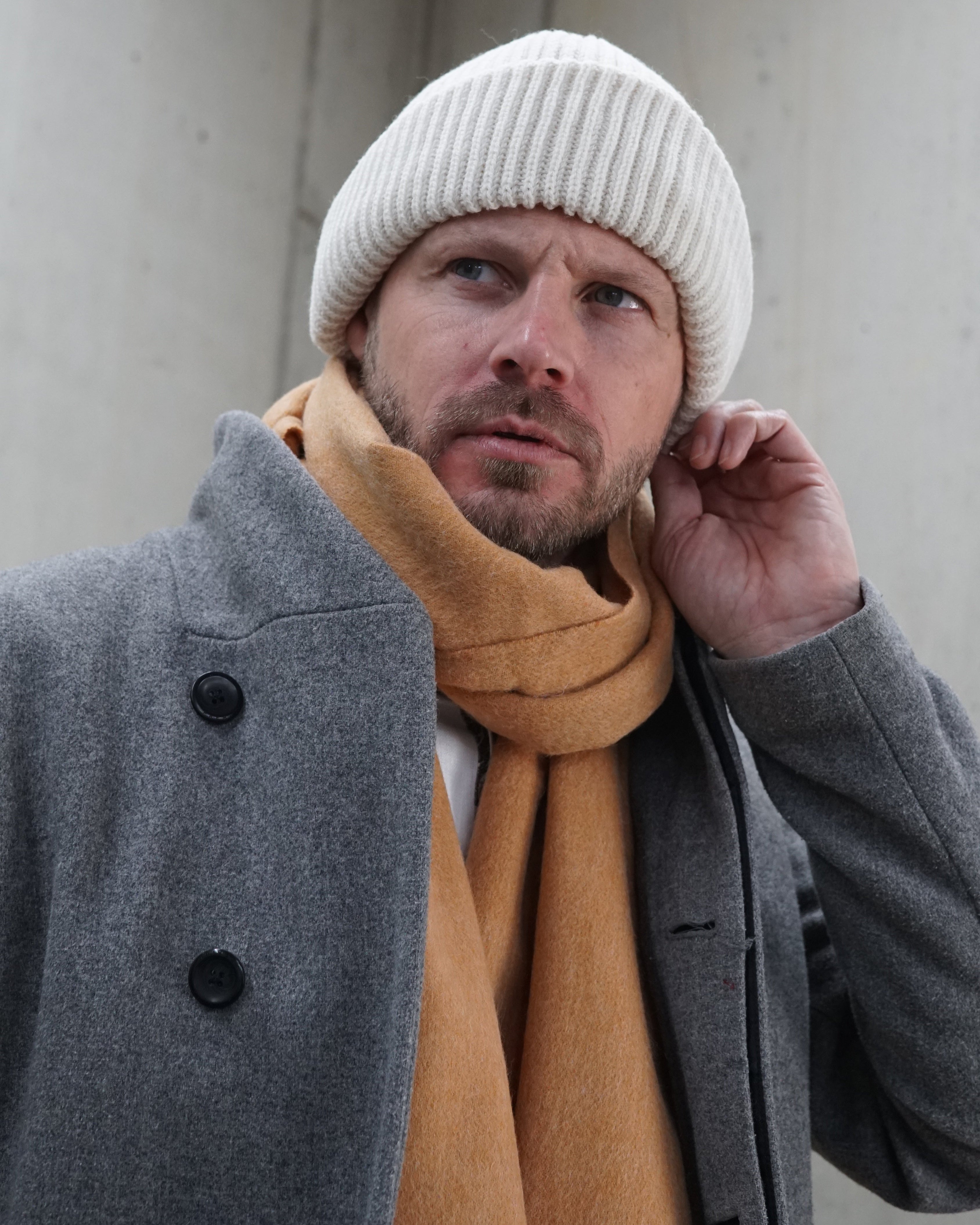 Schal „Caramel Warmth“ aus 100% karamellfarbener Schurwolle getragen von einem Mann mit Beanie-Mütze 2