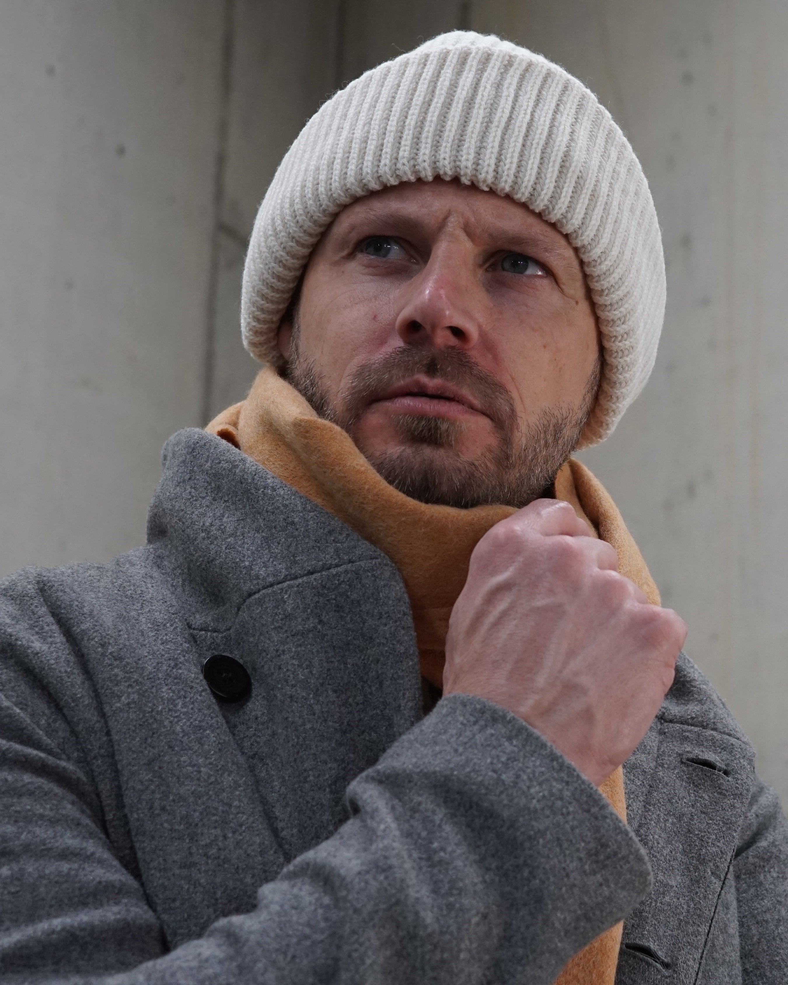 Schal „Caramel Warmth“ aus 100% karamellfarbener Schurwolle getragen von einem Mann mit Beanie-Mütze